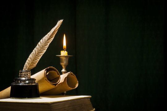The concept of education and writing, a pen in an inkwell and a candle with a candle and a book