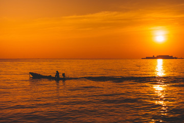 Fototapeta na wymiar Silhouette of fishing boat and fisherman on sunset.