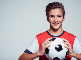 smiling teen boy in sportswear holding soccer ball