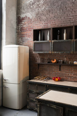 Part of the kitchen in loft style. White refrigerator on brick wall background