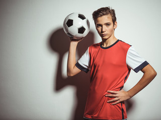 Photo of teen boy in sportswear holding soccer ball