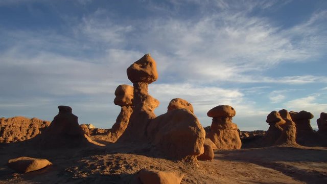 Panning view in Goblin Valley of the hoodoos glowing by the sun light in the evening.