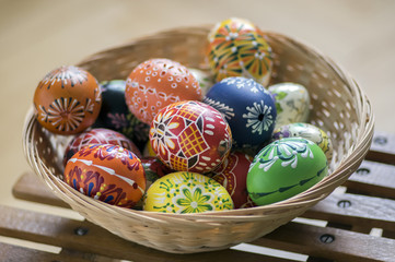 Group of wax painted Easter eggs in light brown wicker basket