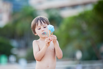 Sweet little child, boy, eating ice cream on the beach