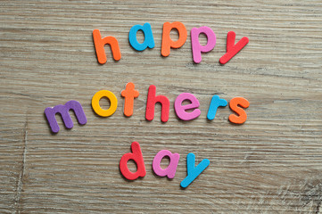 Happy mothers day in colorful letters on a wooden background