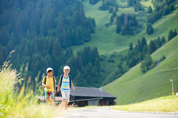 Fototapeta na wymiar Two little children, boy brothers with backpacks travel on the road to scenic mountains