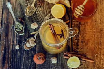 Vitamin medicinal tea with lemon and honey, ginger and spices on wooden background . The concept of spring beriberi and colds.