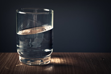 Glas mit Wasser bei falscher Gravitation wie im Film Inception auf Holztisch
