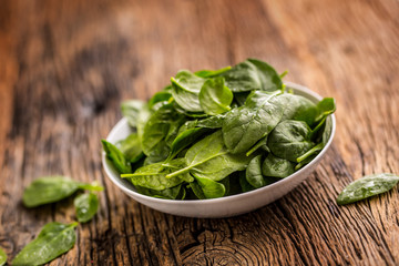 Spinach. Fresh baby spinach leaves in plate on woden table