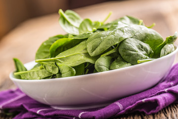 Spinach. Fresh baby spinach leaves in plate on woden table