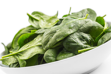 Spinach. Fresh baby spinach leaves in plate isolated on white