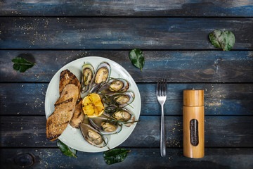 Mussels and bread toasts on on a white plate. Top view