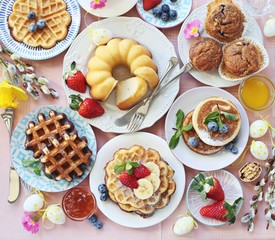 Easter dessert table. Pancakes,waffles and bundt cake with fresh berries and various of topping. Overhead view, copy space