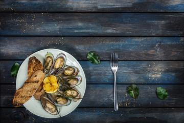 Mussels and bread toasts on on a white plate. Top view