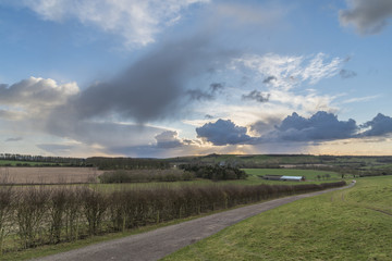 Beautiful stormy moody cloudy sky over English countryside landscape at dusk