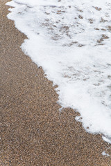 Sea foam on the sandy shore.