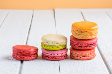 Different types color of macaroons on white wooden background
