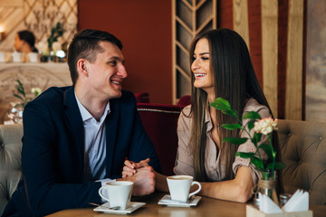 Dating in the cafe. Beautiful young couple sitting in the cafe, drinking coffee Love, dating