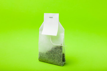 A bag of black tea with an empty label on a green background.