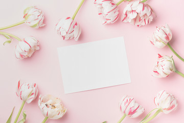 Spring morning concept. Flat-lay of flowers and card over light pink background, top view with space for your text