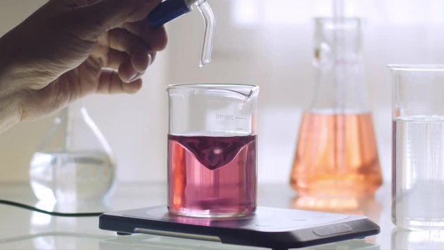 Scientist working with chemical reaction in an Erlenmeyer flask in chemical laboratory