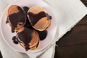 Sweet pancakes with chocolate cream, homemade cooking on a wooden background, top view.