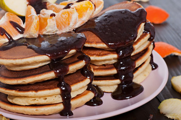 Sweet pancakes with fruit, homemade, on a wooden background.
