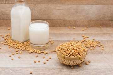 Glass with soy milk and soy bean on wooden background