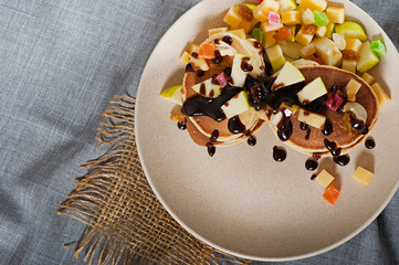 Sweet pancakes with fruits, candied fruits and cheese, homemade, on a light background.