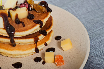Sweet pancakes with fruits, candied fruits and cheese, homemade, on a light background.