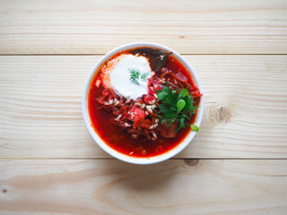 Borsch - beetroot soup in a white bowl on a wooden background, traditional dish of ukrainian cuisine. Top view.
