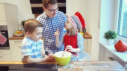 Young father with two happy children backing cookies in modern kitchen