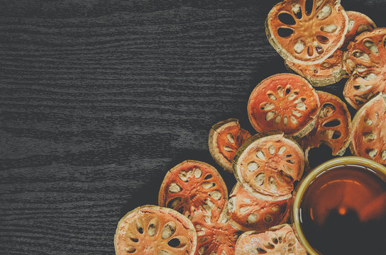Dried herbs and dried bael fruit, Top view of bael dry and glass tea and bael juice on the wooden floor, Slices of bael fruit on the dark table.