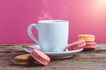 Different types color of macaroons with Cup of hot tea on Old grunge wooden background