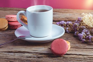 Fototapeta na wymiar Different types color of macaroons with Cup of hot tea on Old grunge wooden background