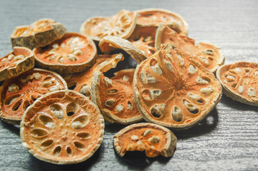 Dried herbs and dried bael fruit, Close-up of bael dry on the wooden floor, Many of slices of bael fruit for make bael juice on the dark table.