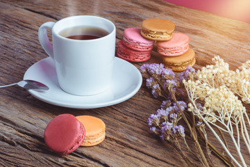 Different types color of macaroons with Cup of hot tea on Old grunge wooden background