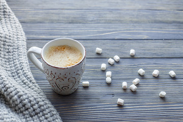 Cup of coffee with marshmallow on a wooden background.