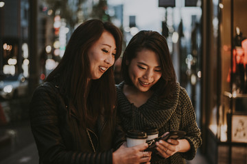 Two japanese women around in Tokyo during daytime. Making shopping and having fun