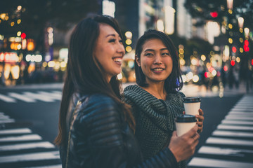 Two japanese women around in Tokyo during daytime. Making shopping and having fun