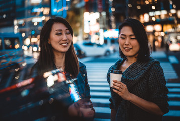 Two japanese women around in Tokyo during daytime. Making shopping and having fun