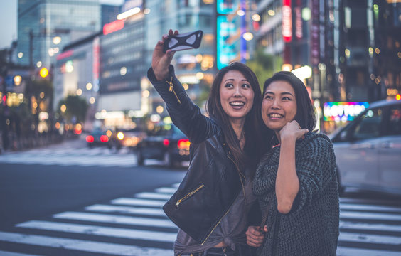 Two japanese women around in Tokyo during daytime. Making shopping and having fun