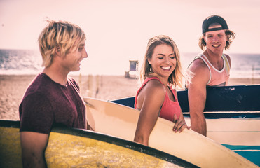 Three surfers walking on the beach carrying their boards