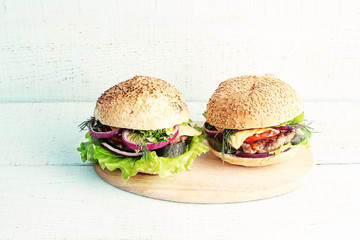 Two burgers on a wooden plate.