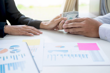 Bribery and corruption concept, bribe in the form of dollar bills, Businessman giving money while making deal to agreement a real estate contract and financial corporate