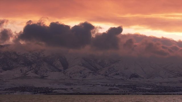 Time lapse of clouds moving across the sky at sunset over Utah lake on a colorful evening in the winter.