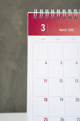 White and red march calendar on wall with cement wall.