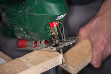 a green jigsaw saws a bright plank