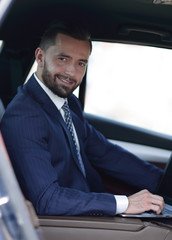 Close-up of a businessman with a laptop sitting in the car