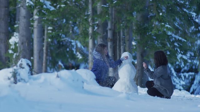 Two girls building a snowman
